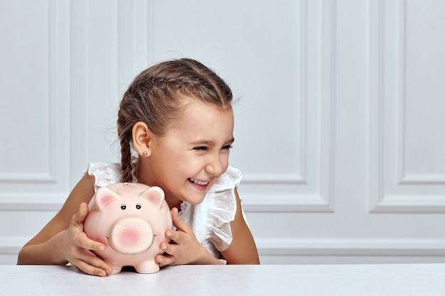 Little child girl with piggy bank at home