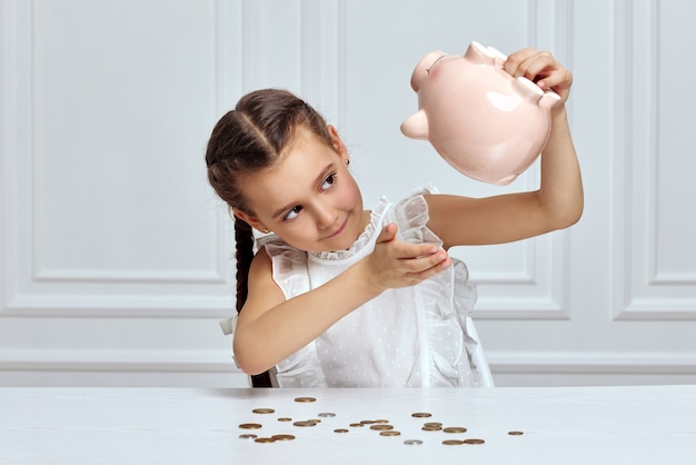 Photo little child girl with piggy bank at home