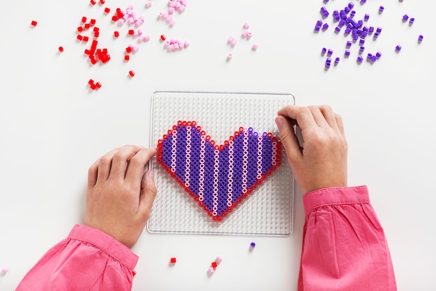 Foto le mani dei bambini piccoli fanno arte perline a forma di cuore