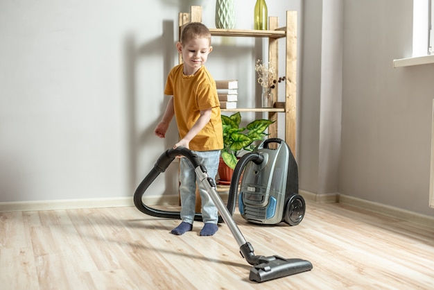 A little child helps his parents in housework, cleaning the floor using a vacuum cleaner