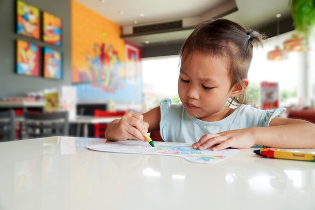 Photo little child intend coloring with crayons in the classroom