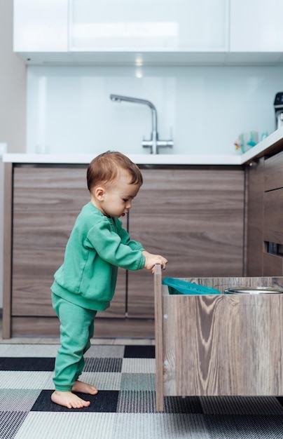 Little child playing with drawer Baby alone in the kitchen Baby safety in kitchen