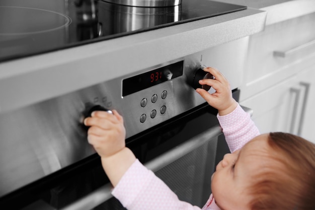 Little child playing with electric stove in the kitchen