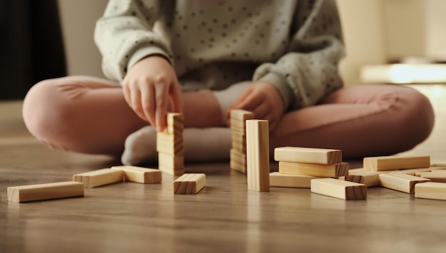 Il bambino gioca a un gioco da tavolo il bambino costruisce con blocchi di mattoni di legno giochi educativi per bambini