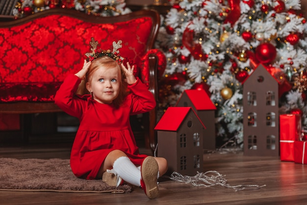 little child in red dress with christmas tree