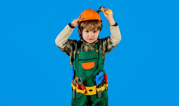 Foto piccolo riparatore bambino in uniforme di costruttore con cintura per attrezzi e martello piccolo ragazzo in casco e