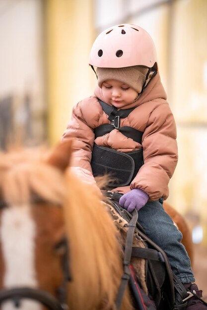 Foto lezione di equitazione per bambini piccoli una bambina di tre anni cavalca un pony e fa esercizi