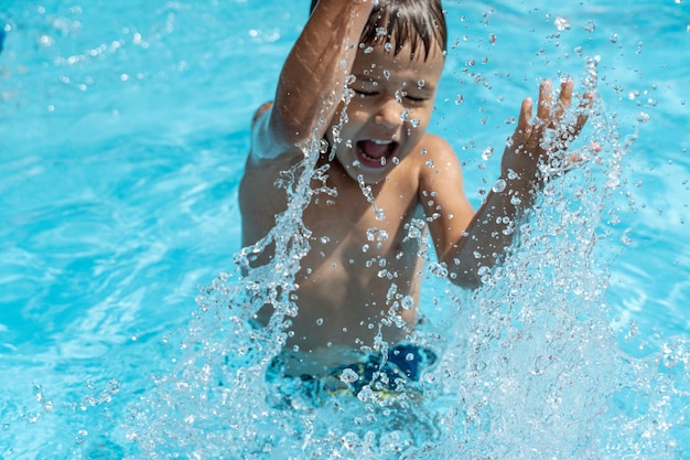 写真 小さな子供はプールで泳ぎ、水しぶきを再生します