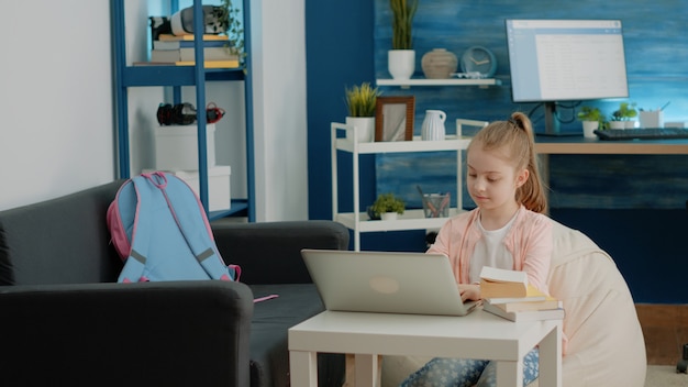 Piccolo bambino che utilizza il laptop per le lezioni scolastiche online a casa