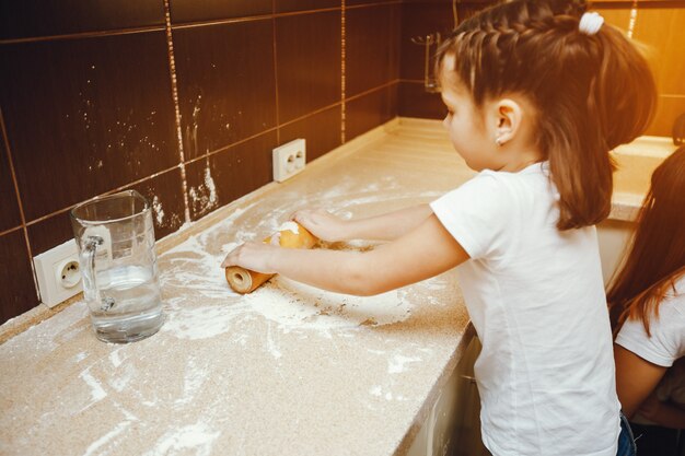 Photo little child in white t-shirt playing at home with flour