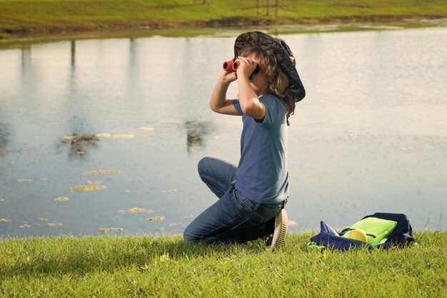 Little child with backpack and binoculars imagination or exploration in park happy child playing