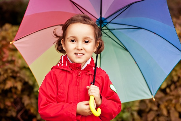 Little child with multicolored rainbow umbrella outdoors.