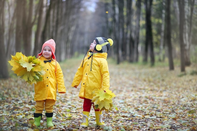 Little children are walking in the autumn park in the fall of leaves