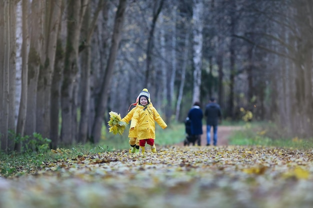 Маленькие дети гуляют в осеннем парке под осенними листьями