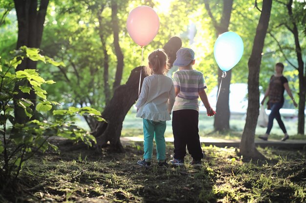 Little children are walking in a park with balloons