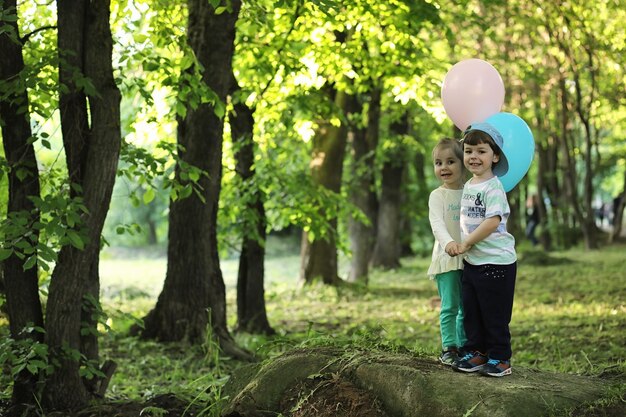 Little children are walking in a park with balloons