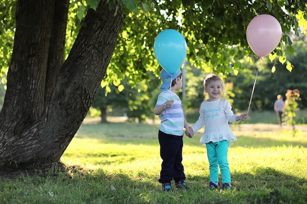 Little children are walking in a park with balloons