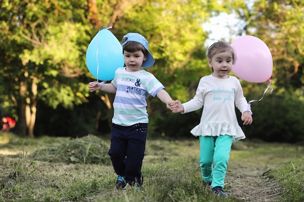 Little children are walking in a park with balloons