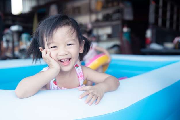 Little children enjoy and have fun playing water in inflatable pool