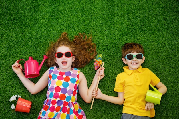 Little children gardeners lying on green grass.