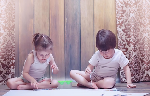 Little children paint on a large sheet of paper