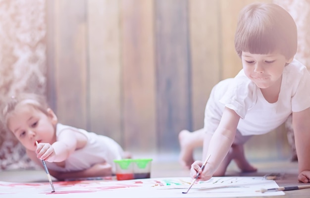 Little children paint on a large sheet of paper