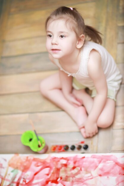 Little children paint on a large sheet of paper