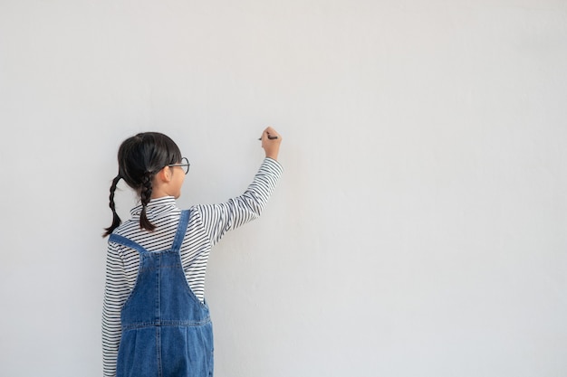 白い壁に絵を描く小さな子供たち