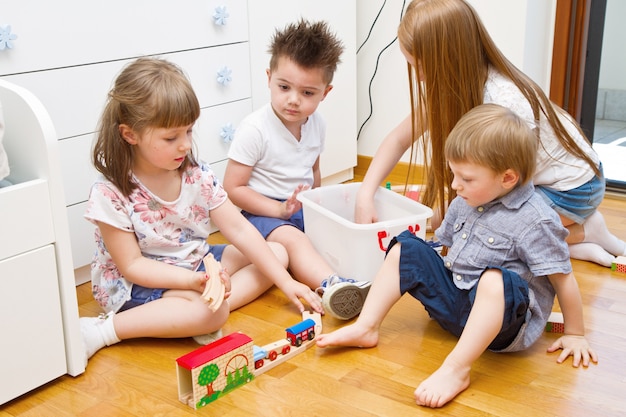 部屋に木製の電車で遊んでいる小さな子供たち