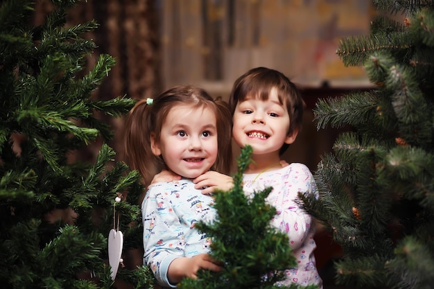 お正月が近づいて喜ぶ小さな子供たち クリスマスツリーの周りで大喜びで遊ぶ子供たち