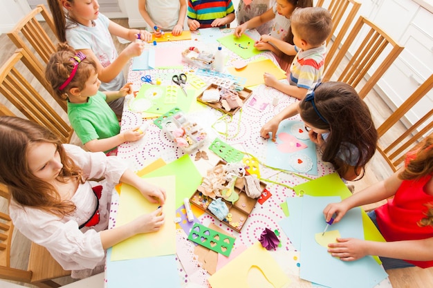 Little children sit together and make greeting cards with their hands