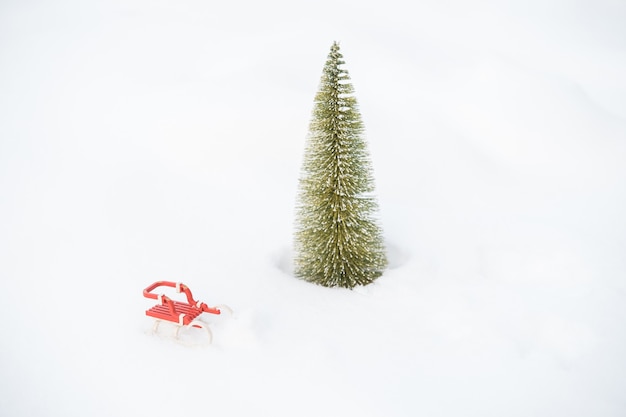 Foto piccolo albero di natale e slitta nella neve all'aperto. buon natale. buon anno. foto di alta qualità