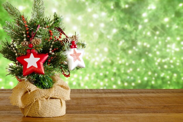 Little christmas tree on wooden table with christmas lights in the green background