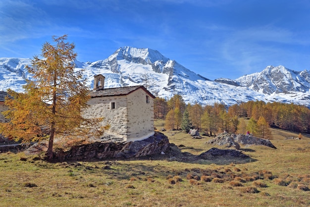 Маленькая церковь во французском альпийском национальном парке перед заснеженной горой под голубым небом