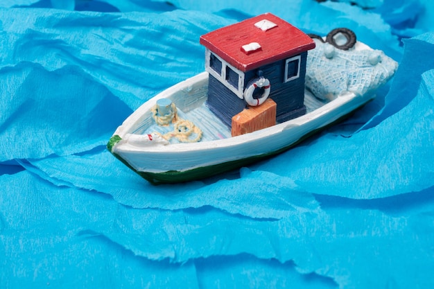 Little colorful model fishing boat on blue