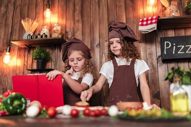 Piccoli cuochi che leggono il ricettario