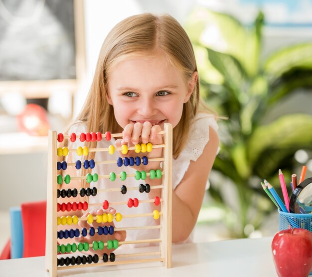 Little counting on the colourful abacus in the school classroom