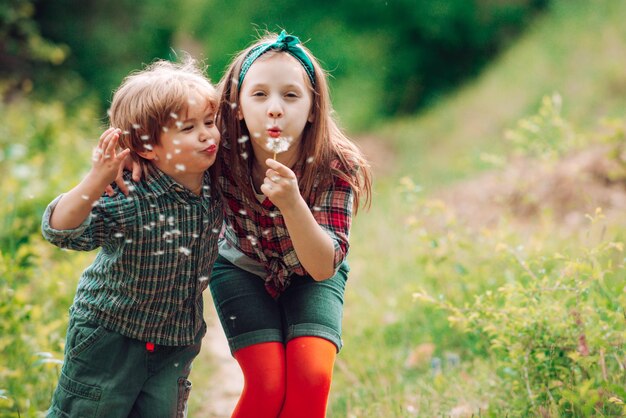 Little couple on Valentines Day Enjoy Nature Cute kids blowing dandelion Kids walking in summer field