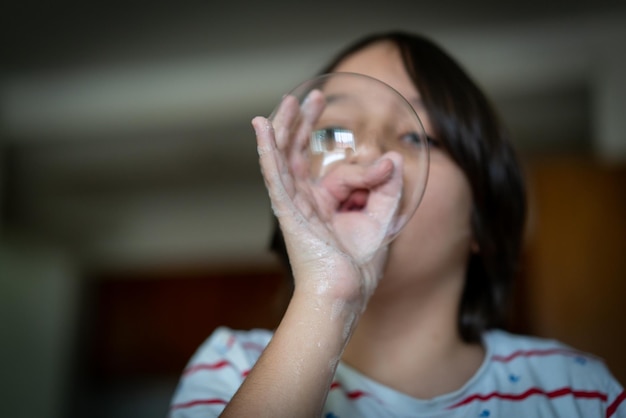 Little creative kid having fun with soap bubble during lockdown