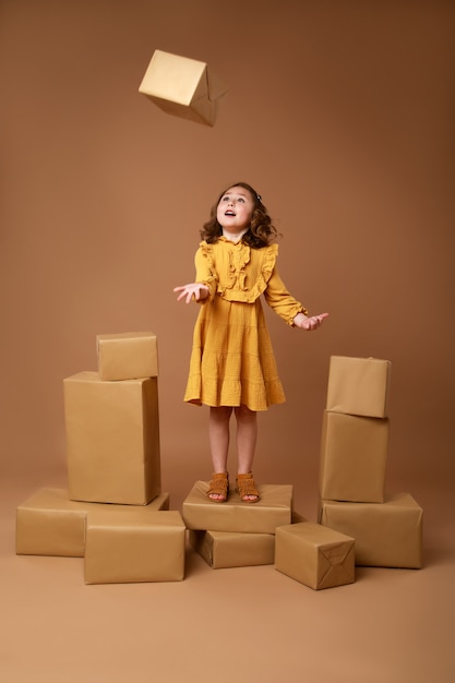 Little curly girl with big stack of gifts for the holiday