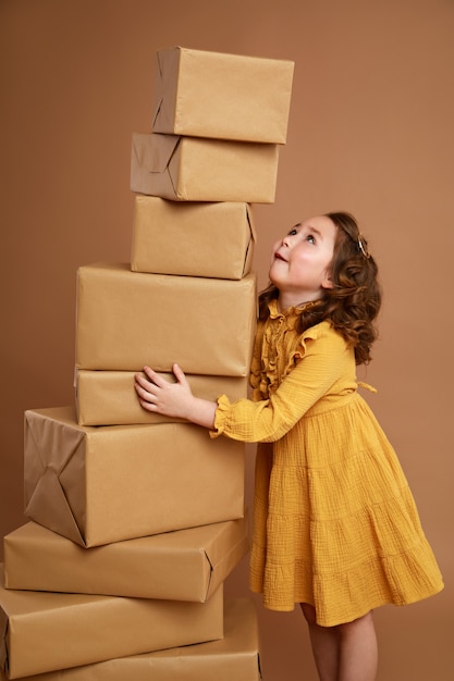 Little curly girl with big stack of gifts for the holiday