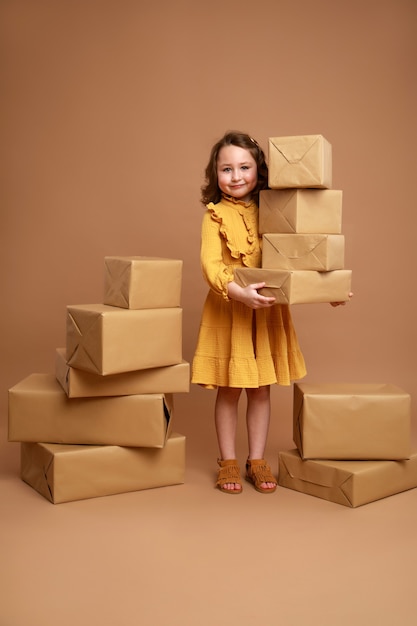 Little curly girl with big stack of gifts for the holiday