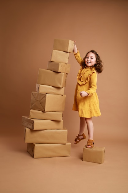 Little curly girl with big stack of gifts for the holiday