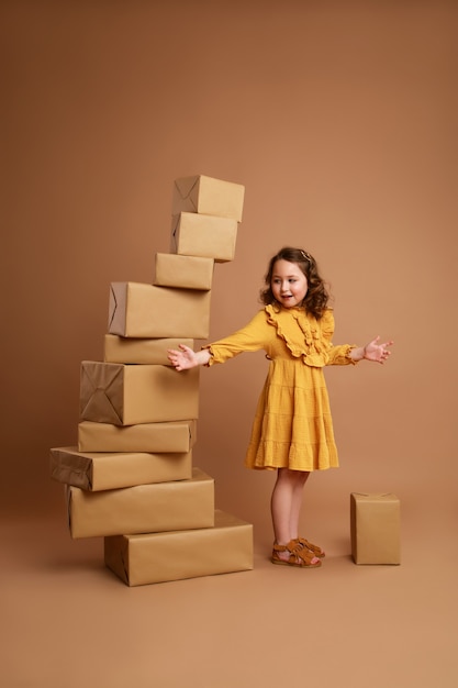 Little curly girl with big stack of gifts for the holiday