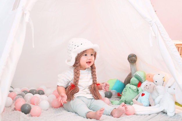 Little cute and adorable asian girl is playing with dolls in teepee tent.