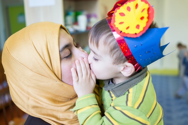 彼の母親を抱きしめてキスする小さなかわいい赤ちゃん少年