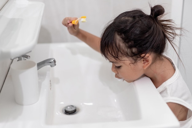 小さなかわいい女の赤ちゃんがバスルームで歯ブラシで歯を掃除