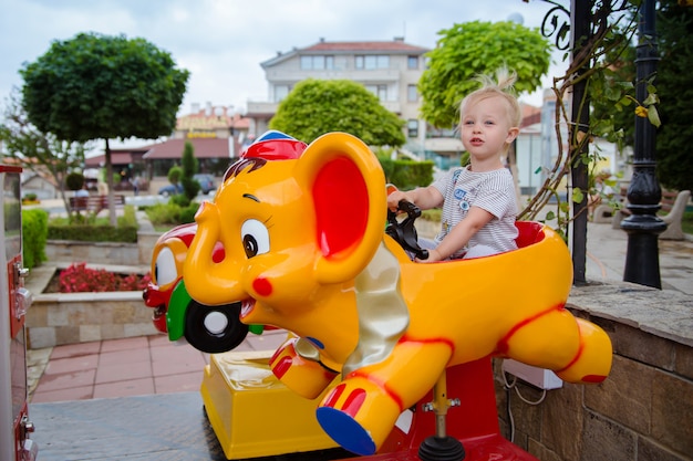 Little cute baby girl riding on the amusement in the park