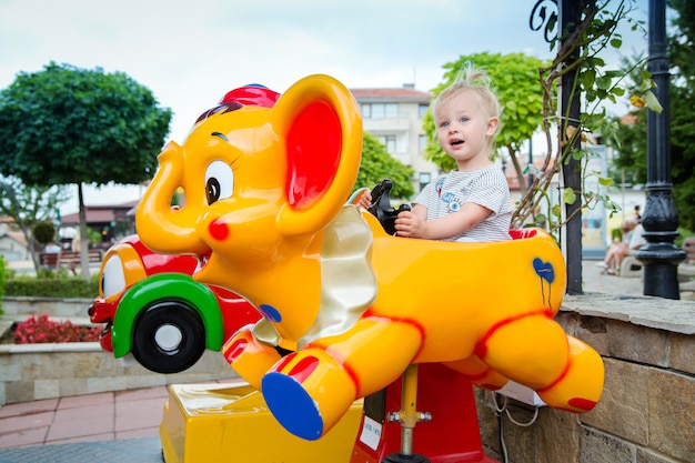 Little cute baby girl riding on the amusement in the park