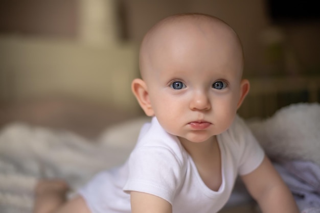 Little cute baby sits on the bed on a white blanket